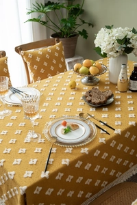 Detail of yellow tufted floral tablecloth with white jacquard patterns and fringe edges