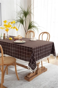 Detail of coffee-colored checkered tablecloth with white tassel edges and cotton texture