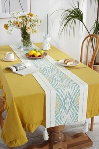 Detail of ginger cotton linen tablecloth with ruffled edges and geometric tassel runner