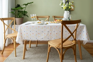 Close-up of cotton tablecloth featuring colorful polka dots and white pompom fringe detail