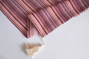 Detail of colorful Bohemian woven tablecloth with geometric patterns and fringe tassels