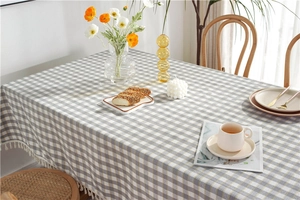 Detailed view of gray plaid tablecloth with white fringe tassels on a dining table