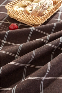 Detail of dark brown checkered tablecloth with woven texture and fringe accents