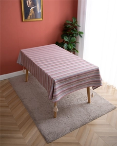 Detail of bohemian floral stripe tablecloth with cotton fringes on a wooden dining table