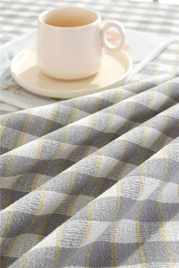 Close-up of yellow and grey plaid tablecloth fabric with woven texture and tassel detail