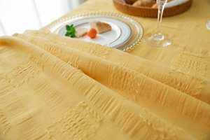 Close-up of yellow cotton tablecloth showing jacquard texture and tufted details