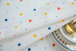 Detail of French cotton tablecloth with colorful ink drops and textured polka dot jacquard