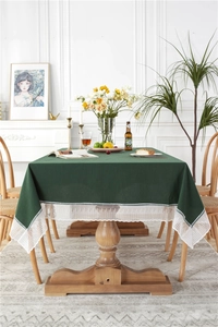 Detail of dark green cotton tablecloth featuring elegant white geometric lace trim edges