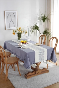Detail of blue cotton tablecloth with ruffle edge and white tassel table runner