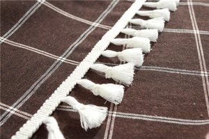 Detailed close-up of dark brown plaid tablecloth with intricate white fringe tassels
