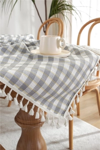 Macro detail of gray and white plaid tablecloth with white cotton tassel fringes