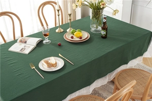 Detailed close-up of dark green washed cotton tablecloth with elegant white lace border trim