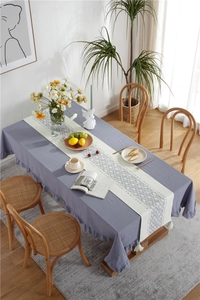 Detail of grey-purple ruffled tablecloth and white tassel table runner with geometric patterns