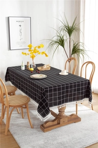 Close-up of black and white checkered tablecloth featuring woven fringe tassels and linen texture