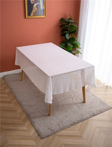 Detailed view of white French lace tablecloth with geometric hollow patterns on wooden table