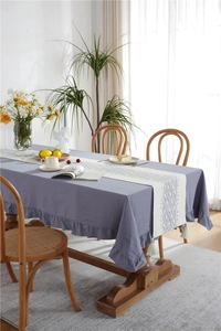 Detail of purple ruffle edge tablecloth paired with a blue geometric tassel runner