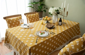 Close-up of yellow jacquard tablecloth with white tufted diamonds and fringe edges