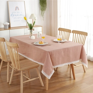 Rectangle pink polka dot tablecloth with white lace edges on a wooden dining table