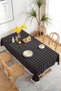 Close-up of black and white plaid tablecloth with elegant white tassel fringe details