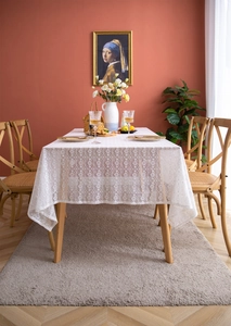 Detail of white French lace tablecloth with hollow geometric patterns on wooden dining table