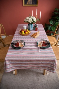 Detailed view of bohemian floral stripe tablecloth with white corner tassels on wood