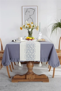 Close-up of gray-purple ruffled cotton tablecloth with light blue diamond pattern runner