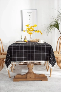 Detailed close-up of black and white grid tablecloth featuring elegant white fringe tassels
