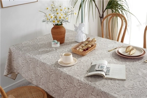 Detailed view of grey floral waterproof tablecloth with white fern leaf patterns and hemmed edges