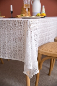 Close-up of white floral lace tablecloth with intricate hollow crochet detailing on a table