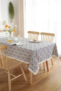 Detail of vintage navy scroll print on beige fabric with delicate white lace edging