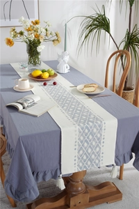 Detail of minimalist geometric diamond texture table runner with white fringe tassels