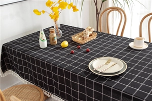 Close-up of black and white checkered tablecloth with tassels in a dining setting