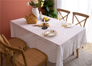 Detail of white lace tablecloth showing intricate hollow floral embroidery and textures
