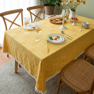 Yellow rectangular cotton tablecloth with jacquard texture and white pompom fringe detail