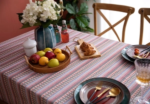 Detail of bohemian floral stripe tablecloth with tassels in a warm rustic dining setting