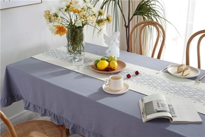 Detail of dark grey-purple cotton tablecloth with ruffle edge and geometric table runner