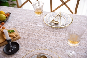 Close-up of ivory lace tablecloth with geometric hollow patterns and 3D floral texture