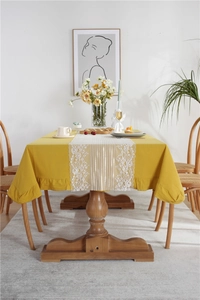 Detail of yellow cotton tablecloth with white lace table runner and ruffled edges