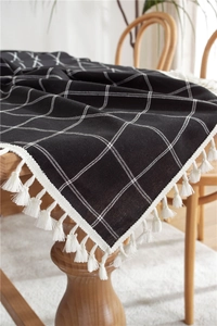 Detailed view of black and white checkered tablecloth with decorative cotton tassels
