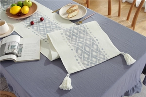 Detail showing Nordic cotton table runner with grey diamond patterns and white tassels