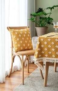 Detail of bohemian yellow tablecloth with white tufted diamond pattern and tassel trim