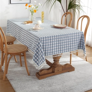 Blue and white checkered plaid rectangular tablecloth with tassel edges on a wooden dining table