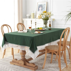 Elegant dark green washed cotton tablecloth with white lace trim on a wooden dining table