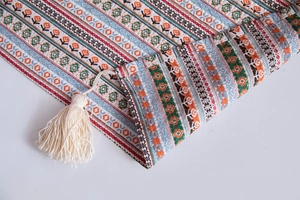 Close-up of woven floral patterns and cream cotton tassels on Bohemian tablecloth