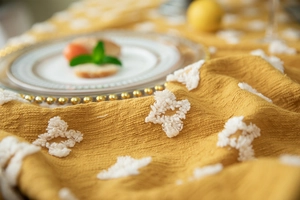 Detail of tufted geometric pattern on mustard yellow cotton tablecloth with rich texture