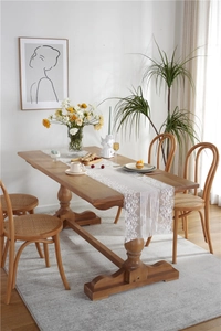 Close-up of white floral lace table runner with scalloped edges on a wooden dining table
