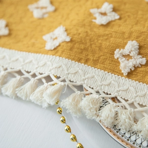 Detail of vintage ginger yellow jacquard tablecloth with white star tufting and tassels