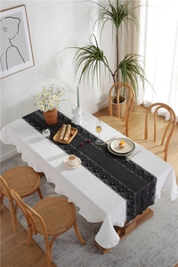 Detail view of a black table runner featuring vertical stripes and exquisite lace edges