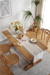 Close-up of white floral lace table runner with embroidery on a rustic wooden dining table