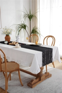 Detail showing the intricate black lace runner with elegant white ruffled tablecloth edge
